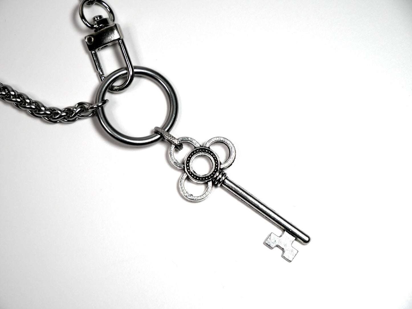 Metallic key charm on a chain against a white background. Devotion Clasp Collar. Handcrafted biblical womanhood jewelry USA. Tradition chain. Stainless Steel.
