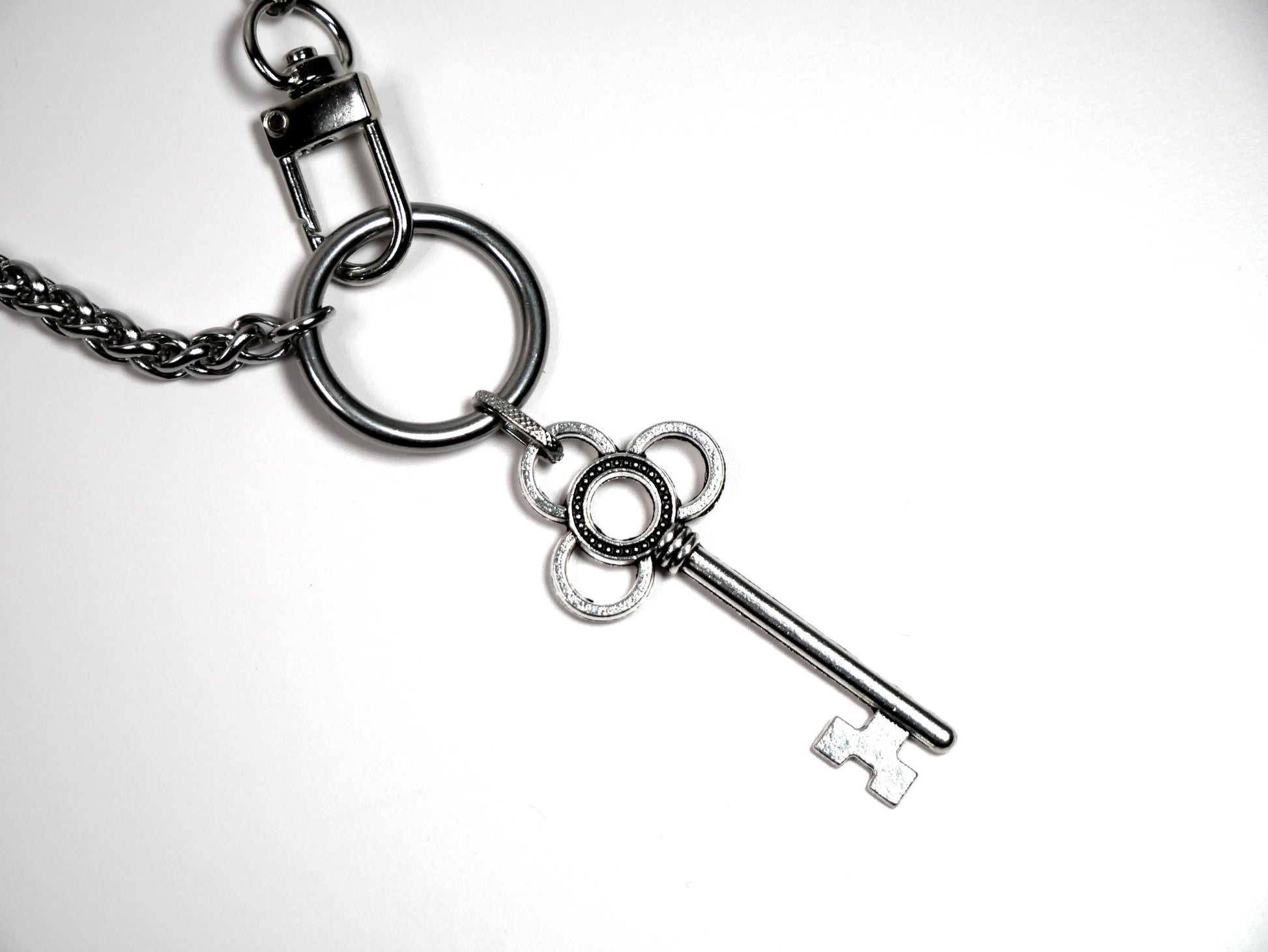 Metallic key charm on a chain against a white background. Devotion Clasp Collar. Handcrafted biblical womanhood jewelry USA. Tradition chain. Stainless Steel.